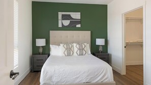 A bedroom with a bed, two nightstands, a headboard, a wall art piece, and a closet. - Landing | Stylish 2BD, Gym, Courtyard (Goodyear)
