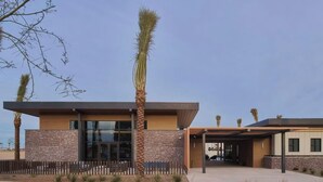 A modern building with a stone facade, large windows, and a covered entrance. - Landing | Modern 2BD, Game Room, Gym (Goodyear)