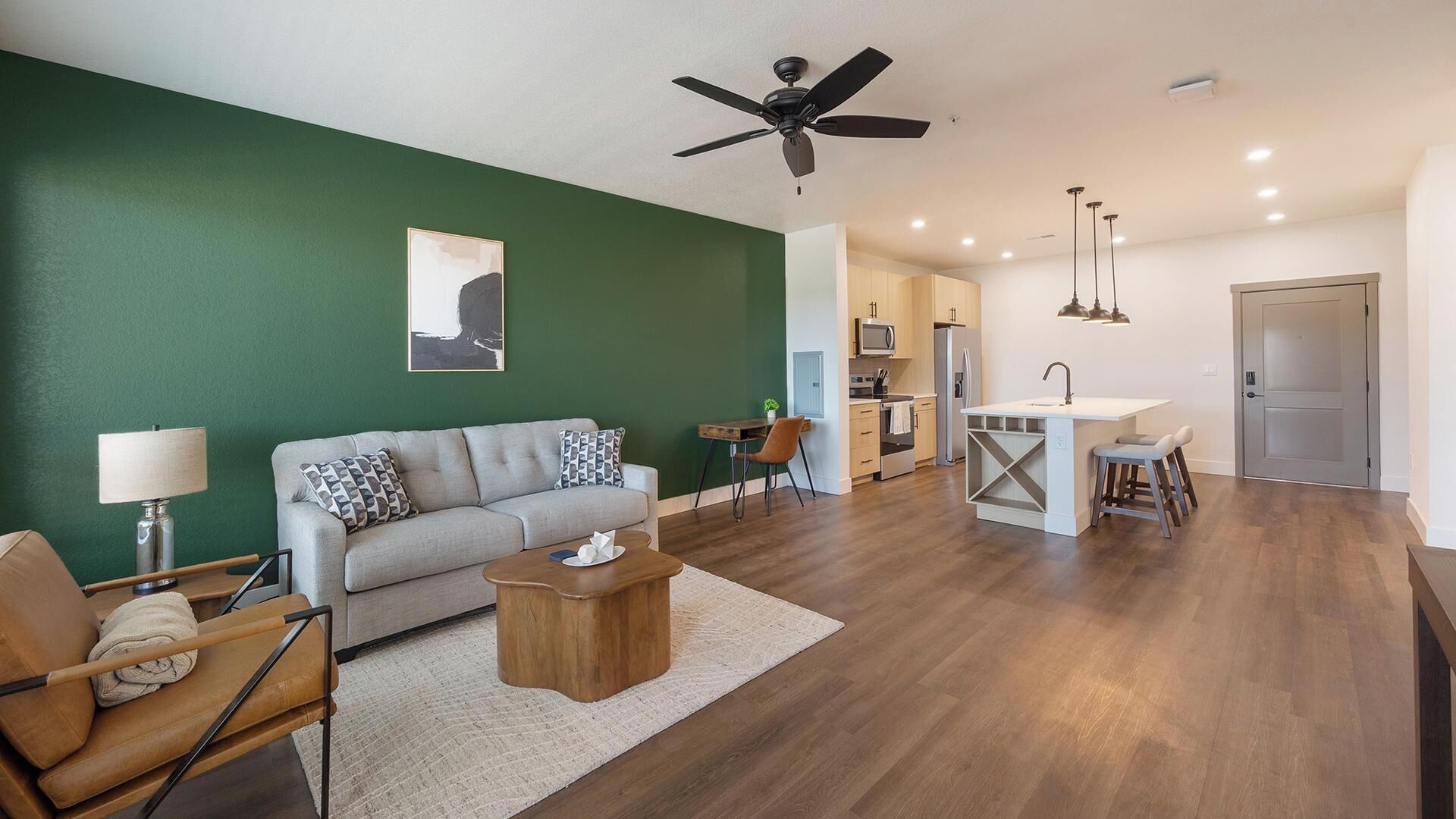 A modern living room with a sofa, coffee table, and a dining area with a kitchen in the background.