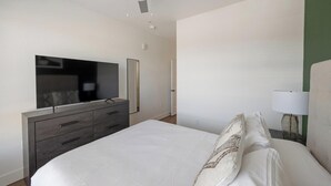 A bedroom with a bed, a dresser, a television, and a lamp. - Landing | Spectacular 1BD, Gym, Courtyard (Goodyear)
