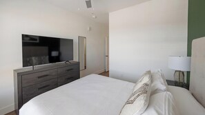 Ein Schlafzimmer mit einem Bett, einem Schminktisch, einem Fernseher und einer Lampe.