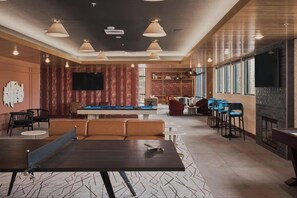 Uma área de estar moderna com mesa de bilhar, assentos e lareira.