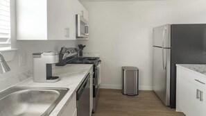 Une cuisine moderne dotée d’appareils électroménagers en acier inoxydable, d’un plan de travail en marbre et de meubles blancs.