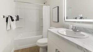 Une salle de bain moderne avec une douche à parois de verre, des toilettes blanches et un lavabo en marbre.