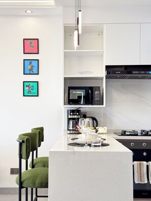 A modern kitchen with a central island, a microwave, a coffee maker, and a gas stove. - Plum Skyline Kilimani (Nairobi)