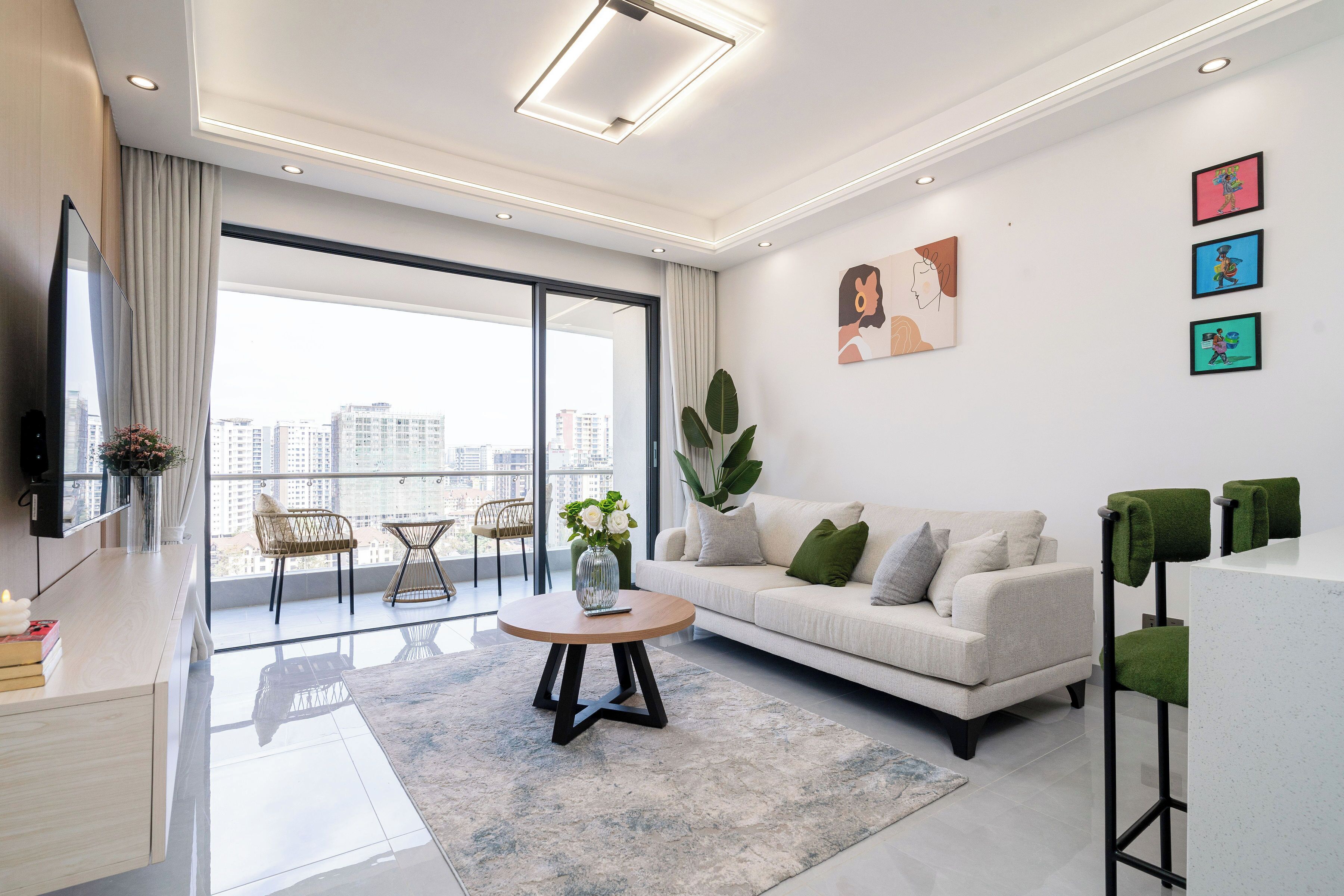En moderne stue med en sofa, et sofabord og udsigt over byen gennem store vinduer.