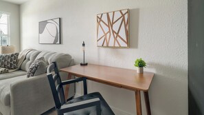 Ein modernes Wohnzimmer mit einer Couch, einem Holztisch und zwei an der Wand befestigten Kunstwerken.
