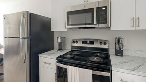 A kitchen with a stainless steel refrigerator, a microwave, a stove, and a coffee maker.