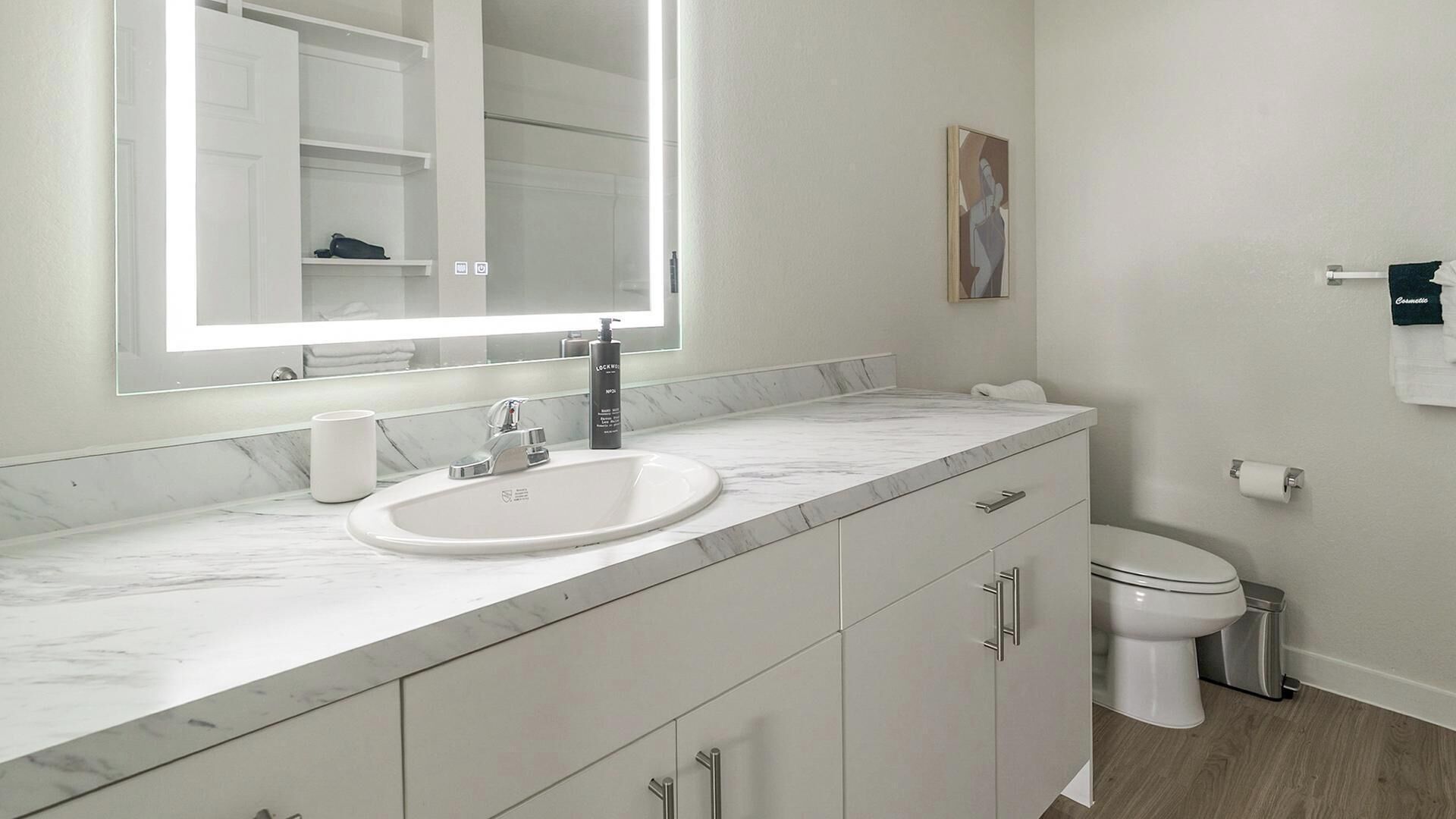 Een moderne badkamer met een grote spiegel, een wastafel en een toilet.