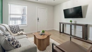 Un salon avec un canapé, une table basse, un téléviseur et une porte.