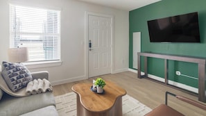 Ein Wohnzimmer mit Sofa, Couchtisch, Fernseher und Kamin.