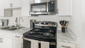 Una cocina moderna con electrodomésticos de acero inoxidable, un lavamanos doble y encimeras de mármol.