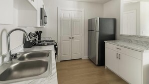 A kitchen with a double sink, stainless steel appliances, and white cabinetry. - Landing | Beautiful 1BD in Bear Creek (Houston)