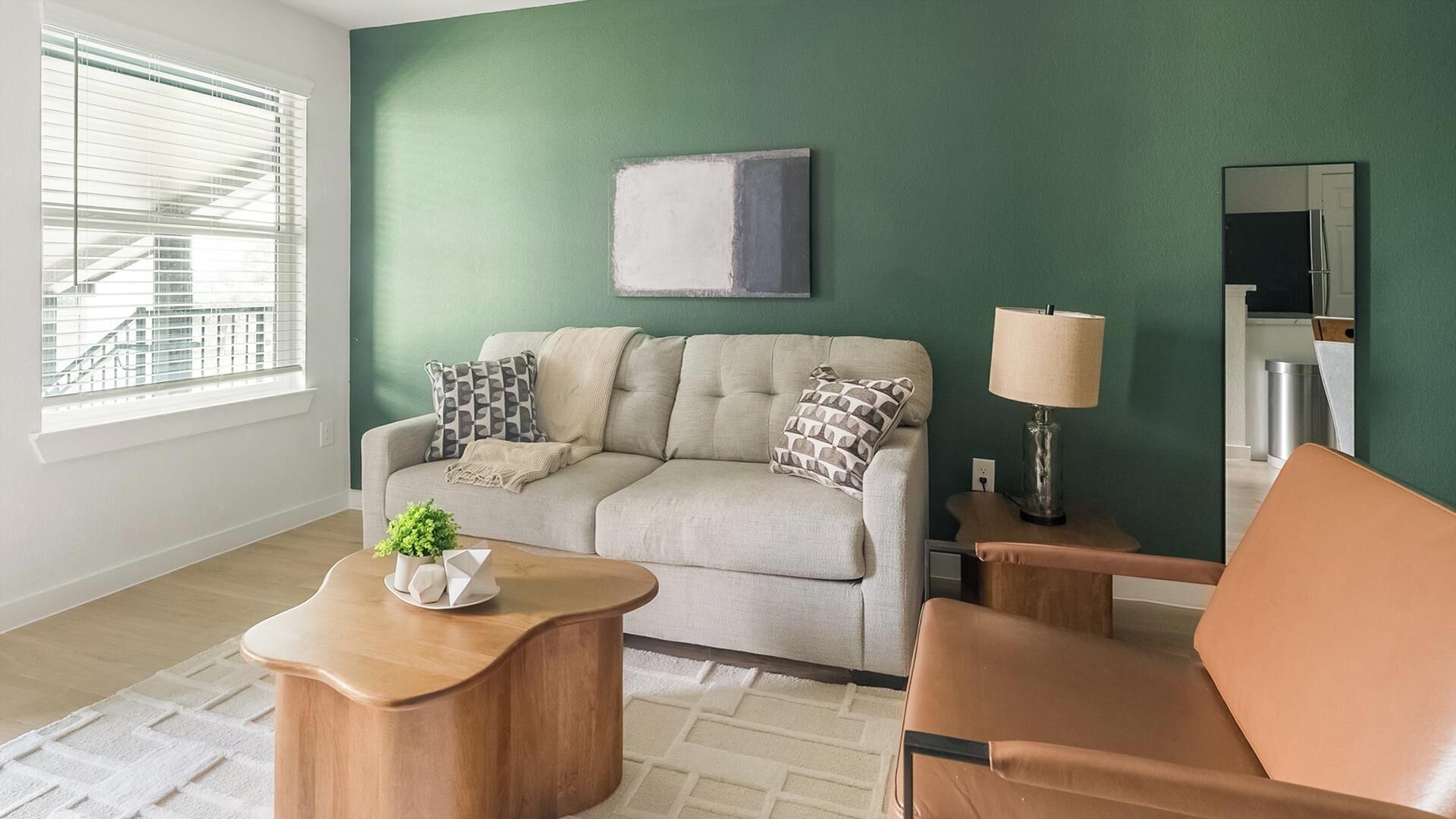 A living room with a sofa, a coffee table, a chair, a lamp, and a painting on the wall.