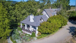 Ein Haus mit Veranda, umgeben von dichtem Grün und einem Schotterweg.