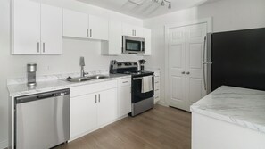 A modern kitchen with white cabinets, stainless steel appliances, and a marble countertop. - Landing | Beautiful 1BD in Bear Creek (Houston)