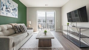 Ein modernes Wohnzimmer mit einer Couch, einem Couchtisch und einem Fernseher auf einem Lowboard.