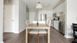 Eine moderne Küche mit weißen Schränken, Edelstahlgeräten und einem Holzespeisetisch mit grau gepolsterten Stühlen.