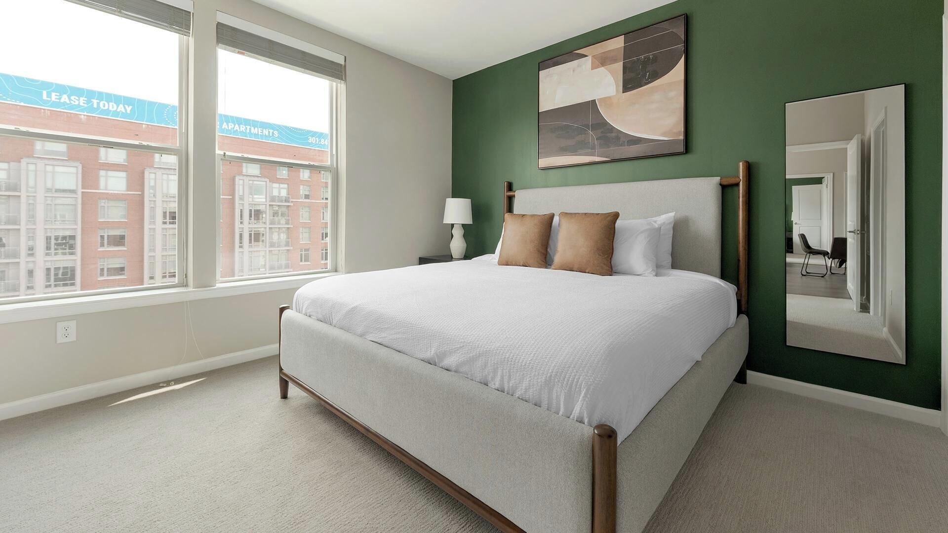 A bedroom with a bed, a nightstand, a window, and a green wall.