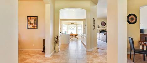 A spacious hallway with a dining area, kitchen, and a living room with a fireplace.