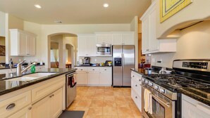 A modern kitchen with white cabinetry, stainless steel appliances, and a black granite countertop. - Peace of Mind by Avantstay Fenced BBQ Yard + Game Table Paso Robles (Paso Robles)