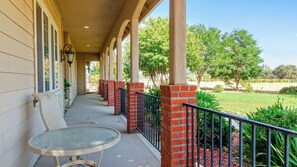 A covered porch with a glass table and chairs, brick pillars, and a view of a grassy area with trees. - Peace of Mind by Avantstay Fenced BBQ Yard + Game Table Paso Robles (Paso Robles)
