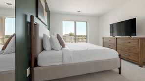 A bedroom with a bed, a television, and a view of the outdoors. - Landing | Chic 2BD, Rooftop Lounge, Gym (Chevy Chase)