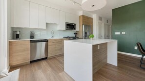 A modern kitchen with white cabinetry, stainless steel appliances, and a central island. - Landing | Chic 2BD, Rooftop Lounge, Gym (Chevy Chase)
