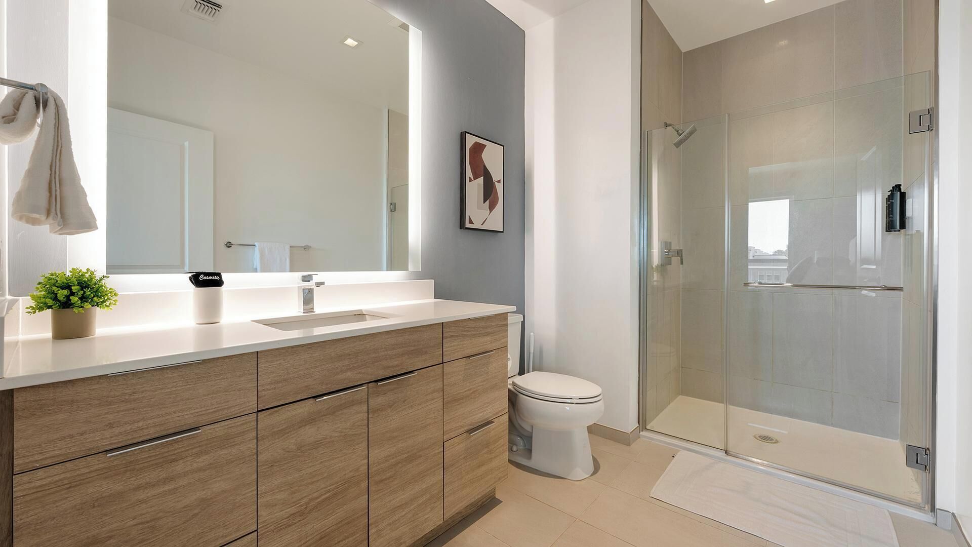 Une salle de bain moderne avec un meuble-lavabo en bois, un grand miroir, des toilettes et une douche à parois de verre.