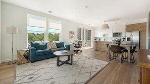 A modern living room with a sofa, coffee table, and a view of the outdoors. - Landing | Stylish 2BD, Gym, Rooftop Lounge (Chevy Chase)