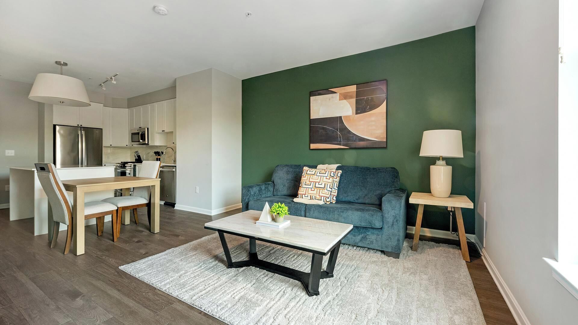 A modern living room with a sofa, coffee table, and a painting on the wall.