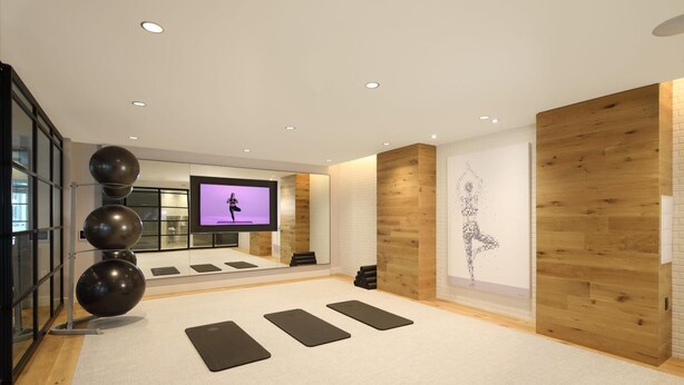 A modern fitness room with a large screen, exercise balls, and yoga mats. - Landing | Spectacular 1BD, Gym, Rooftop Lounge (Chevy Chase)
