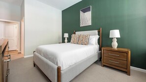 A neatly arranged bedroom with a bed, bedside tables, and a door. - Landing | Incredible 1BD, Gym, Rooftop Lounge (Chevy Chase)