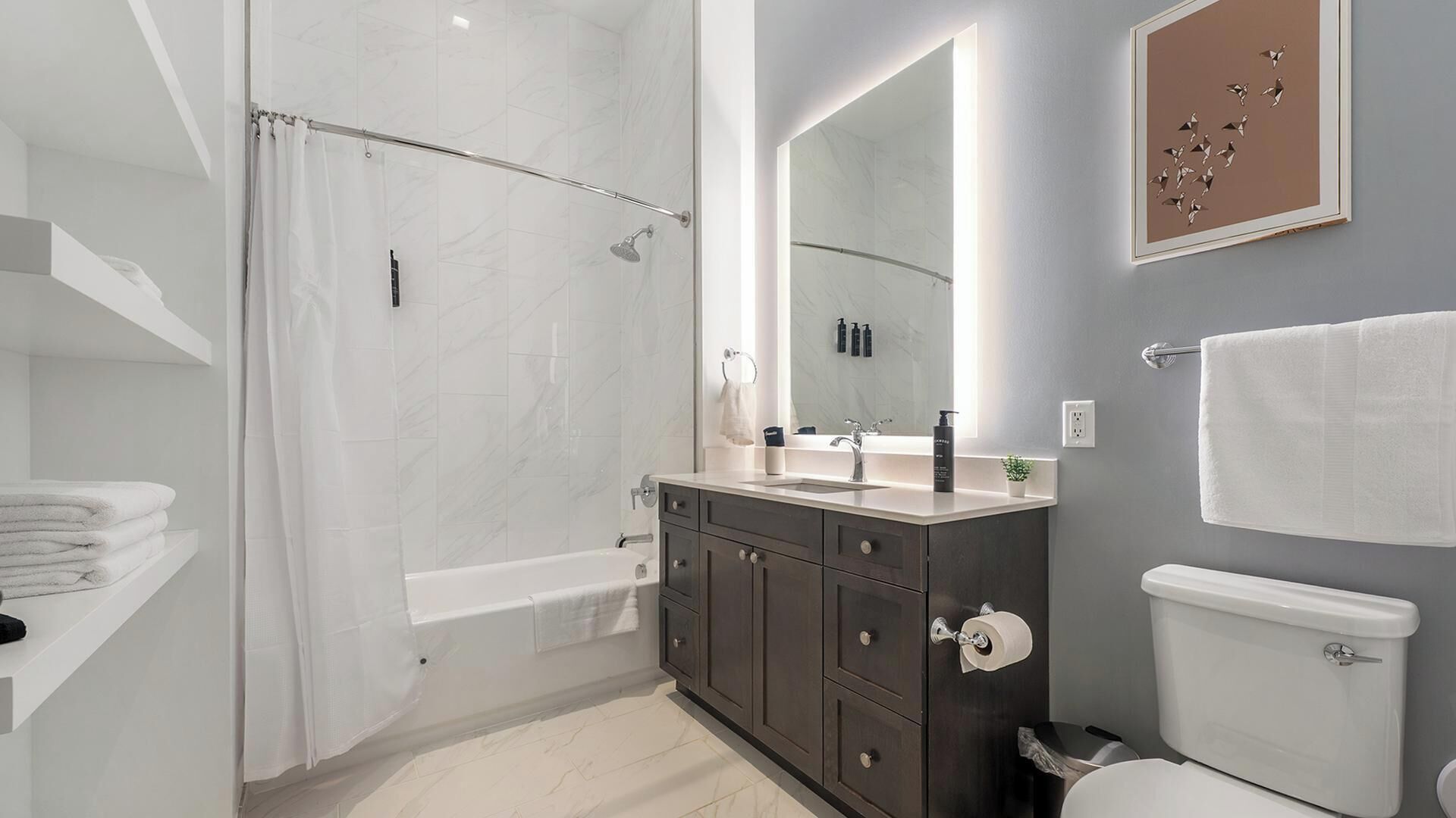 Un baño moderno con ducha a ras de suelo, tocador con espejo y inodoro.