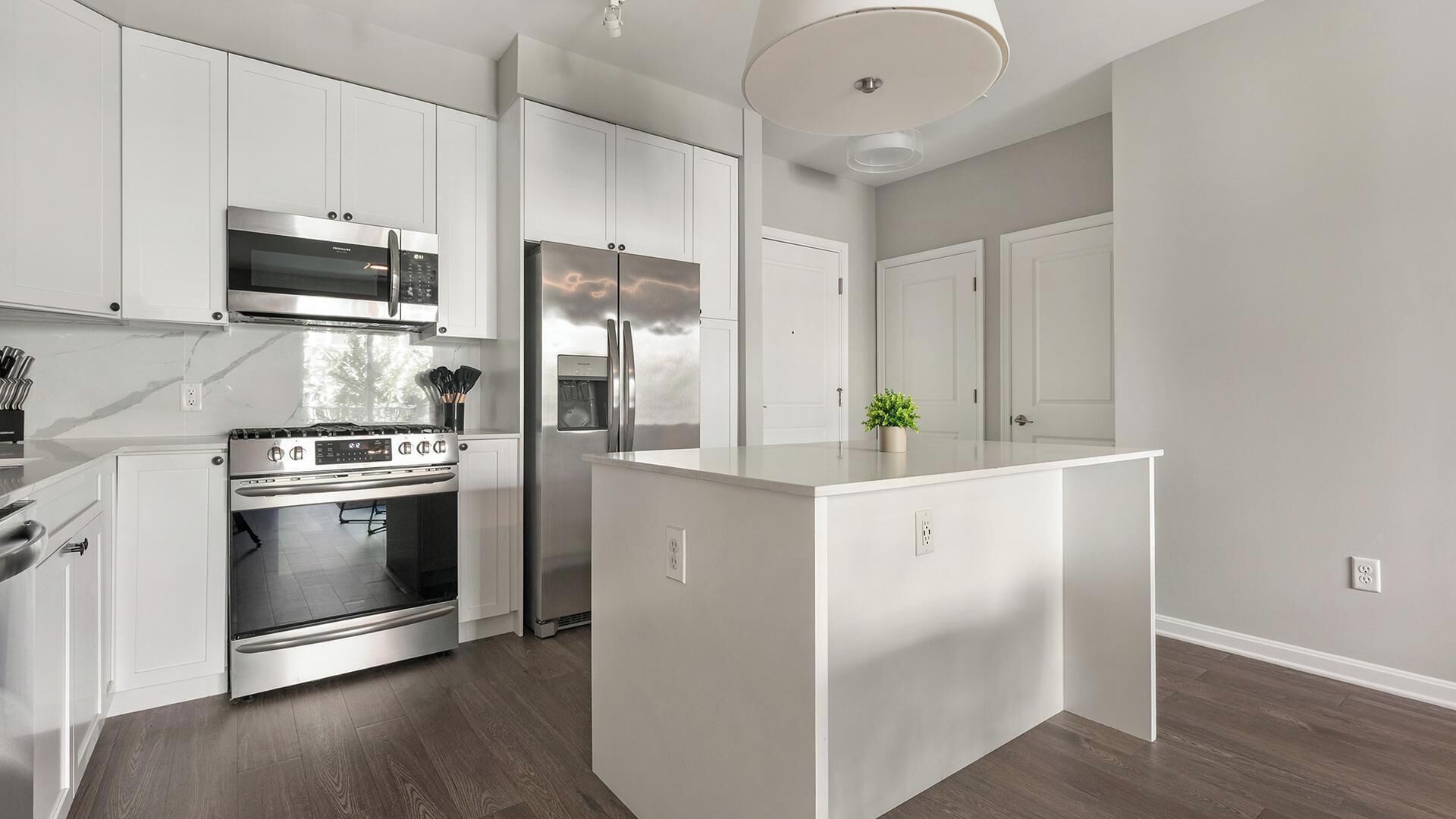 A modern kitchen with white cabinetry, stainless steel appliances, and a central island.