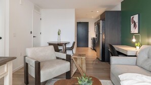 A modern living room with a sofa, a coffee table, and a dining area with chairs. - Landing | Modern 1BD, Courtyard, Pool (Orlando)