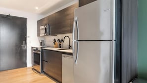 A modern kitchen with a stainless steel refrigerator, a microwave, and a coffee maker on the countertop. - Landing | Stylish 1BD, Rooftop Lounge, Gym (Orlando)