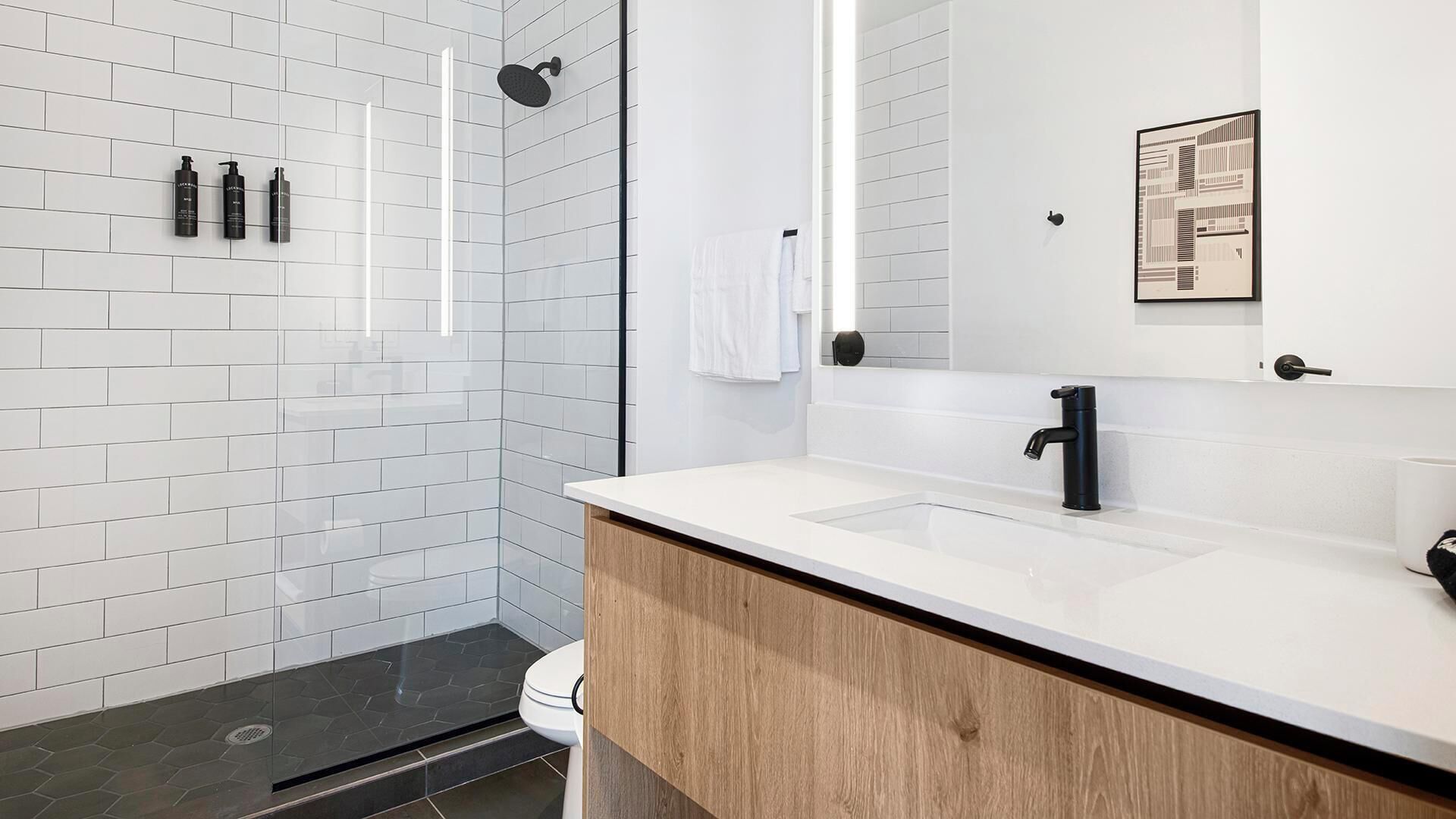 Een moderne badkamer met douche, toilet en wastafel.