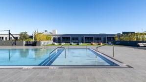 A rooftop swimming pool with a clear view of a modern building in the background. - Landing | Stylish 2BD, Courtyard, Pool (Orlando)