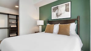 A hotel room with a bed, a nightstand, a lamp, and a wall-mounted artwork. - Landing | Incredible 1BD, Gym, Rooftop Lounge (Orlando)