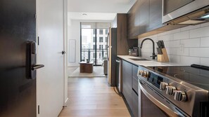 A modern kitchen with a stainless steel range, a built-in oven, and a black faucet. - Landing | Incredible 1BD, Gym, Rooftop Lounge (Orlando)