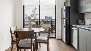 A modern kitchen with a large window, a dining area with two chairs, and a refrigerator. - Landing | Beautiful 2BD, Gym, Pool (Orlando)