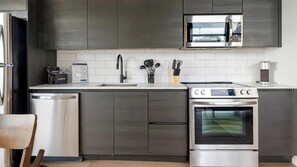 A modern kitchen with stainless steel appliances, a built-in oven, and a microwave. - Landing | Beautiful 2BD, Gym, Pool (Orlando)