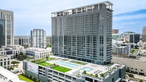 A high-rise building with a rooftop pool and a landscaped terrace. - Landing | Beautiful 2BD, Gym, Pool (Orlando)