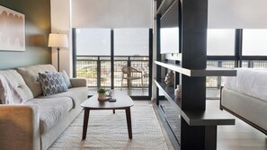 A modern living room with a sofa, a coffee table, and a TV stand. - Landing | Stylish Studio, Pool, Rooftop Lounge (Orlando)