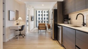A modern kitchen with a built-in dishwasher, a sink with a black faucet, and a countertop with a water bottle and a box labeled 'LANDING'. - Landing | Stylish 1BD, Gym, Pool (Orlando)
