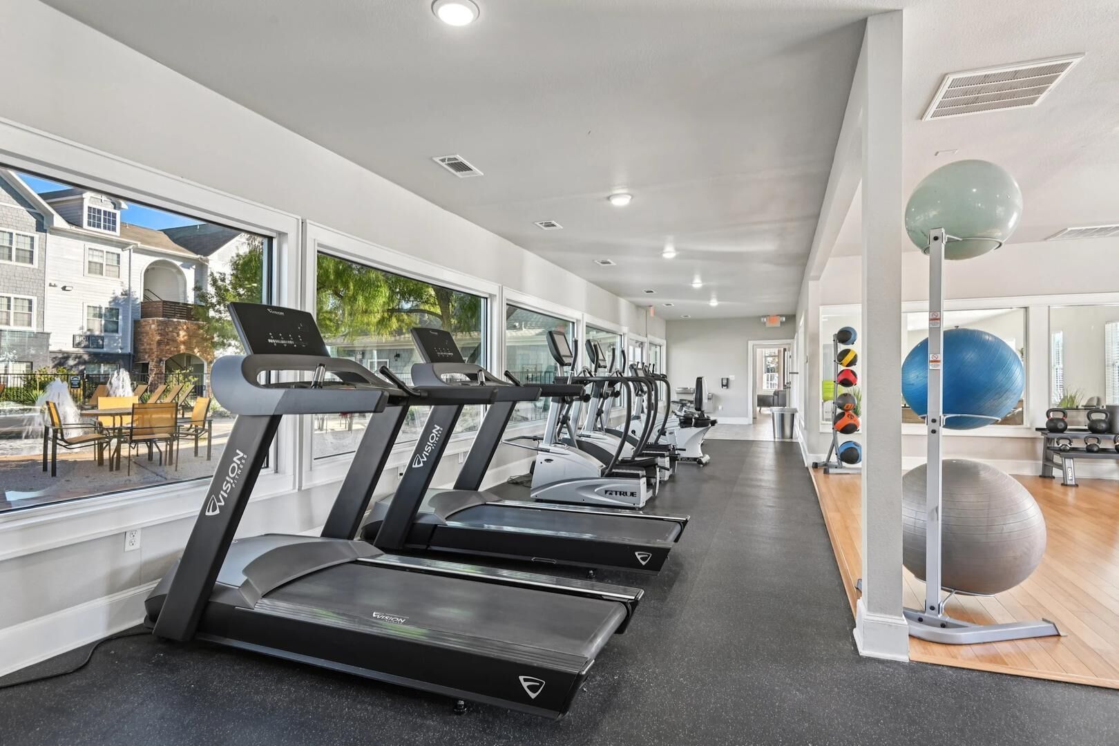 Ein Fitnessstudio mit Laufbändern, Gymbällen und Blick nach draußen.