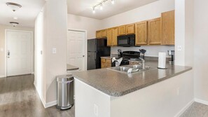 A modern kitchen with granite countertops, stainless steel appliances, and wooden cabinets. - Landing | Amazing 3BD, Game Room, Gym (Fort Worth)