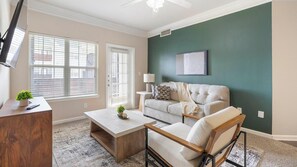 A living room with a sofa, coffee table, and a TV on a stand. - Landing | Amazing 3BD, Game Room, Gym (Fort Worth)
