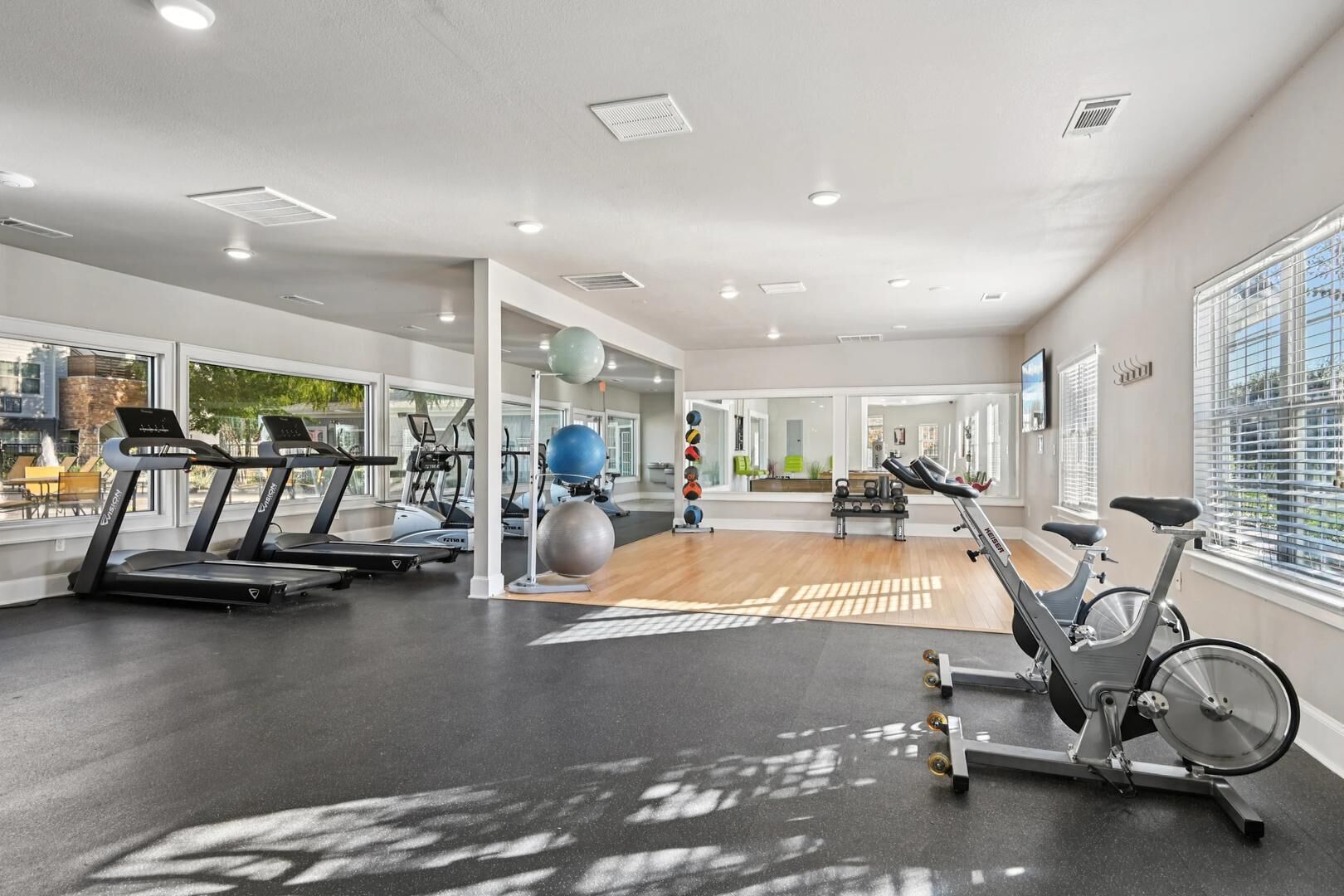 A gym with treadmills, stationary bikes, and exercise balls.